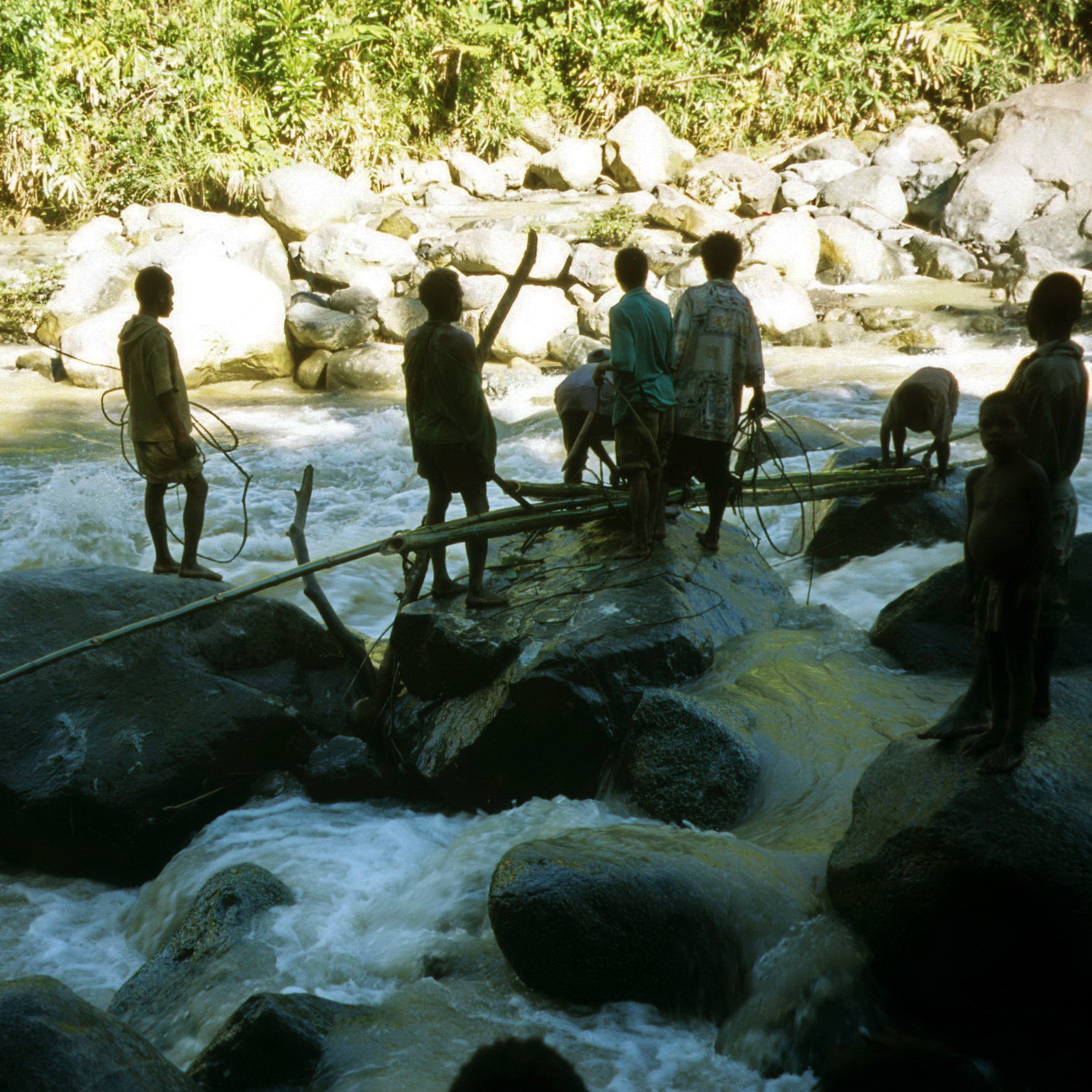 Where there is no bridge, make one.  Hiring some local guys to put up a flimsy makeshift bridge across a small river.  It looks reasonably tame in the photo but as I recall we went to all that trouble because it was too dangerous to cross on foot.